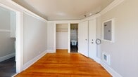 Located on the fifth floor of a building in Portland's vibrant downtown core, this studio unit offers an efficient and thoughtfully laid-out living space. The main living area is bathed in natural light streaming through a large sliding window, which frames an open city view and fills the warm hardwood floors with sunlight throughout the day. Crown molding runs along the ceiling, lending a classic architectural detail that adds character to the compact space.

The kitchen is efficiently arranged, featuring a gas range, a sink with dark granite-style countertops, and cabinetry, all positioned beneath a window that allows additional natural light. The bathroom is a standout, offering a charming vintage clawfoot bathtub, a pedestal sink, corner shelving, and wainscoting that gives the room a classic, timeless feel. Dark hardwood flooring in the bathroom contrasts neatly with the white fixtures and wall trim.

A dedicated closet provides built-in hanging storage, keeping the living area uncluttered. The unit's neutral color palette of soft whites and warm grays ties each area together cohesively. Overall, this space combines historic charm with practical function, making it a characterful urban retreat in the heart of Portland.