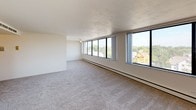This well-appointed two-bedroom, two-bathroom residence offers a thoughtfully designed single-floor layout with a clean, neutral palette throughout. The expansive living area is carpeted and bathed in natural light through large floor-to-ceiling windows that frame sweeping urban and neighborhood views, creating an open and airy atmosphere. Baseboard heating runs along the perimeter of the main living spaces, ensuring year-round comfort. The kitchen features dark espresso-toned cabinetry paired with light countertops and wood-look flooring, and is equipped with a full suite of white appliances including a refrigerator, electric range, dishwasher, and sink. Both bedrooms are generously sized with plush carpeting and ample natural light. One bedroom includes double bi-fold closet doors providing excellent storage capacity, while the other offers city views through a large corner window. The two bathrooms are functionally appointed — one featuring a tub-shower combo with tiled surround and a vanity with a marble-style countertop, and the second offering a standalone shower with glass doors and a built-in vanity. The overall design is clean and understated, offering a versatile canvas well-suited to a variety of living arrangements.