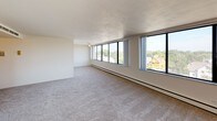 This well-appointed two-bedroom, two-bathroom residence offers a thoughtfully designed single-floor layout with a clean, neutral palette throughout. The expansive living area is carpeted and bathed in natural light through large floor-to-ceiling windows that frame sweeping urban and neighborhood views, creating an open and airy atmosphere. Baseboard heating runs along the perimeter of the main living spaces, ensuring year-round comfort. The kitchen features dark espresso-toned cabinetry paired with light countertops and wood-look flooring, and is equipped with a full suite of white appliances including a refrigerator, electric range, dishwasher, and sink. Both bedrooms are generously sized with plush carpeting and ample natural light. One bedroom includes double bi-fold closet doors providing excellent storage capacity, while the other offers city views through a large corner window. The two bathrooms are functionally appointed — one featuring a tub-shower combo with tiled surround and a vanity with a marble-style countertop, and the second offering a standalone shower with glass doors and a built-in vanity. The overall design is clean and understated, offering a versatile canvas well-suited to a variety of living arrangements.