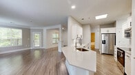 Located at 3770 George Busbee Pkwy in Kennesaw, GA, this well-appointed 2-bedroom, 2-bathroom single-floor home offers a thoughtfully designed layout with modern finishes throughout. The open-concept kitchen and living area serves as the heart of the home, featuring white shaker cabinets with matte black hardware, quartz countertops, a large island with an undermount sink, and stainless steel appliances including a range, microwave, and refrigerator with ice maker. Wood-look flooring flows through the main living areas, complementing the bright, neutral color palette. The living room is anchored by an electric fireplace flanked by two large windows that invite abundant natural light and views of the surrounding greenery. A private balcony extends the living space outdoors. The spacious primary bedroom includes plush carpeting and a generous walk-in closet with wire shelving. The second bedroom also features carpet and its own closet. Both bathrooms are finished with tile-surround tub/shower combos, white vanities, and wood-look flooring. A dedicated laundry room houses a full-size Whirlpool front-load washer and dryer. The attached garage provides convenient parking and additional storage. Four closets throughout the home ensure ample storage at every turn.