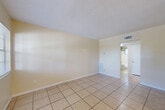 Located in Saint Petersburg, Florida, this single-story unit offers a practical and well-organized layout comprising a bedroom, bathroom, kitchen, and hallway. Light-toned ceramic tile flooring runs consistently throughout the space, contributing to a clean, cohesive look that also suits Florida's warm climate.

The bedroom is a comfortable, well-proportioned room featuring a ceiling fan with light fixture and a window that admits natural light and views of surrounding greenery. Neutral beige walls and white trim keep the space feeling bright and open. A second view of the bedroom reveals a ceiling vent for climate control and a doorway leading into the hallway, connecting the room to the rest of the unit.

The galley-style kitchen is efficiently arranged, featuring white cabinetry, a top-freezer refrigerator, an electric range, a sink, and light tile backsplash. The compact layout makes practical use of available space, with overhead cabinets providing additional storage.

The bathroom includes a full soaking tub with white subway-style tile surround and a frosted-glass window above, allowing natural light while maintaining privacy. The overall ambiance of the unit is clean, straightforward, and functional, reflecting a no-frills Florida residence.
