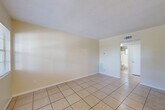 Located at 3545 30th Ave N in Saint Petersburg, Florida, this efficient one-bedroom, one-bathroom unit offers a well-organized single-floor layout. Light-colored ceramic tile flooring runs consistently throughout every room, creating a cohesive, easy-to-maintain interior well-suited to Florida's climate.

The open living area is bright and airy, with neutral cream-toned walls and a textured ceiling. A hallway connects the main living space to the bedroom and bathroom, providing a clear and functional flow. The galley-style kitchen is positioned along one side of the unit and features white cabinetry, a white electric range, and a full-size refrigerator, along with a sink and tile backsplash — offering practical utility in a compact footprint.

The bedroom is a comfortable size, fitted with a ceiling fan, a window that brings in natural light and views of surrounding greenery, and direct access to the hallway. The bathroom includes a full bathtub with white tile surround extending to the walls, and a frosted glass window that allows natural light while maintaining privacy.

Throughout the unit, consistent HVAC venting and wall-mounted heating units ensure year-round comfort. The clean, minimal design and durable finishes make this Saint Petersburg unit a straightforward and functional living space.