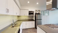 This well-appointed single-floor residence offers a clean, contemporary design throughout. The kitchen is a standout feature, showcasing white shaker-style cabinetry with brushed chrome hardware, dark quartz countertops, and a light-toned subway tile backsplash that adds a subtle decorative touch. Stainless steel appliances, including a full-size refrigerator and built-in microwave, provide a polished, modern look. A double basin sink is positioned beneath recessed lighting that brightens the space efficiently. A distinctive diamond-pattern wine rack built into the upper cabinetry adds a charming architectural detail. Wood-look flooring ties the space together with warmth and durability.

The residence is situated within a multi-story community complex that offers impressive outdoor amenities. The shared courtyard features a resort-style swimming pool surrounded by lounge seating and lined with tall, mature palm trees, creating a relaxed, warm-weather atmosphere. The overall exterior architecture presents a contemporary multi-building design with a cohesive color palette of warm earth tones. Covered parking is also available within the community. The combination of thoughtfully updated interiors and well-maintained community amenities makes this space a comfortable and attractive place to call home.