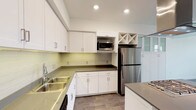 This well-appointed single-floor residence offers a clean, contemporary design throughout. The kitchen is a standout feature, showcasing white shaker-style cabinetry with brushed chrome hardware, dark quartz countertops, and a light-toned subway tile backsplash that adds a subtle decorative touch. Stainless steel appliances, including a full-size refrigerator and built-in microwave, provide a polished, modern look. A double basin sink is positioned beneath recessed lighting that brightens the space efficiently. A distinctive diamond-pattern wine rack built into the upper cabinetry adds a charming architectural detail. Wood-look flooring ties the space together with warmth and durability.

The residence is situated within a multi-story community complex that offers impressive outdoor amenities. The shared courtyard features a resort-style swimming pool surrounded by lounge seating and lined with tall, mature palm trees, creating a relaxed, warm-weather atmosphere. The overall exterior architecture presents a contemporary multi-building design with a cohesive color palette of warm earth tones. Covered parking is also available within the community. The combination of thoughtfully updated interiors and well-maintained community amenities makes this space a comfortable and attractive place to call home.