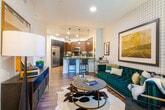 Located at 27665 Forbes Rd in Laguna Niguel, California, this thoughtfully designed one-bedroom residence offers a seamless blend of modern aesthetics and functional living. The open-concept kitchen is a standout feature, showcasing rich dark walnut cabinetry, a deep teal subway tile backsplash, sleek gray quartz countertops, and a central island with pendant lighting. Stainless steel appliances — including a gas range, built-in microwave, dishwasher, and a full-size side-by-side refrigerator — complete the chef-inspired space. Wide-plank hardwood flooring flows throughout the main living areas, connecting the kitchen to a comfortable living room accented by a bold grid-tiled feature wall. The bedroom is a tranquil retreat, offered in two distinct styling options: one featuring a dramatic, moody cloud mural accent wall, and the other with clean, neutral tones — both complemented by a modern ceiling fan and natural light through slatted window blinds. The bathroom is finished with large-format slate tile flooring, teal accent walls, built-in shelving, a soaking tub with shower, and a backlit vanity mirror. An in-unit washer and dryer complete this well-appointed home.