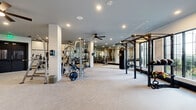 Located at 3200 Meadow Gate Ln in Davenport, FL, this expansive fitness center offers a thoughtfully designed, single-floor layout that provides ample space for a full range of workout activities. The facility is organized into multiple open exercise zones, each outfitted with commercial-grade equipment including Matrix treadmills, stationary bikes, rowing machines, cable machines, multi-station strength systems, free weights, kettlebells, stability balls, and a dedicated heavy bag and power rack area for functional training.

The interior design is clean and modern, featuring light neutral carpeting, white shiplap-accented columns, and smooth gray ceilings with recessed lighting and multiple ceiling fans throughout for comfort and air circulation. Full-length mirrors line key walls, visually expanding the space and providing essential form-checking capability during workouts.

Large windows allow abundant natural light to filter in, creating a bright and energizing atmosphere while offering views of the surrounding Florida landscape. Black-framed glass partition doors and bold dark trim add a contemporary contrast to the light interior palette. The entry corridor features posted fitness rules and access to additional rooms, ensuring a well-organized experience. Overall, the facility delivers a professional, well-equipped environment suited for diverse fitness needs.