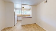 Located at 2075 Langhorne Rd in Lynchburg, Virginia, this single-floor residence offers a practical and well-organized layout across two bedrooms, one bathroom, and a dedicated kitchen. The interior is finished with neutral white walls and wall-to-wall carpeting throughout the living and bedroom areas, creating a clean, understated aesthetic.

The kitchen is efficiently designed with white cabinetry, ample upper and lower storage, light countertops, a built-in electric range, and a refrigerator. A pass-through window connects the kitchen to the adjacent living area, enhancing the sense of openness. The tile flooring in the kitchen provides a functional contrast to the carpeted living spaces.

The primary bedroom is generously proportioned, featuring double louvered bifold closet doors for ample storage and windows that invite natural light and outdoor views of surrounding greenery. The second bedroom similarly benefits from dual windows, filling the room with natural light and views of the landscape beyond.

The bathroom includes a full tub and shower combination with white tile surround, offering a clean and practical design. Throughout the residence, the layout flows efficiently, making good use of the available space. Overhead ventilation and multiple electrical outlets are present throughout, supporting everyday functionality.