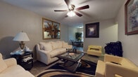 Located at 5323 East Harry Street in Wichita, Kansas, this single-floor home offers a well-organized and inviting layout across its main living areas. The living room serves as the heart of the home, featuring vaulted ceilings with a ceiling fan, soft carpeting, and ample space for seating. Decorative touches such as a sunburst mirror and framed wall art add character to the room, while a glass-top coffee table anchors the cozy seating arrangement. Natural light filters in through curtained windows, enhancing the warm ambiance. An open sightline connects the living room to a dedicated dining area, which features tile flooring, a round dark-wood dining table with ornate metal chairs, and a bright window that brings in additional natural light. The kitchen is efficiently arranged with cream cabinetry, dark countertops, tile flooring, and a full-size refrigerator, offering functional workspace and storage. The bedroom provides a quiet retreat with its own ceiling fan and warm color palette. The bathroom is clean and practical, complete with a full bathtub and shower combination, a vanity with storage, and tile flooring. Throughout the home, consistent neutral tones and thoughtful design details create a cohesive and comfortable living environment.