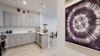 This thoughtfully designed single-floor residence in Bethel, CT offers three bedrooms, two bathrooms, and a well-organized layout that maximizes comfort and functionality. Light-toned hardwood-style flooring flows throughout, creating a cohesive and airy atmosphere.

The kitchen is a standout feature, outfitted with gray shaker-style cabinetry, white quartz countertops, a subway tile backsplash, stainless steel appliances including a gas range and dishwasher, and a peninsula with bar seating — opening seamlessly into the living and dining areas.

The living room is bright and welcoming, featuring large windows that invite natural light and provide outdoor views, complemented by clean white walls and generous floor space.

The primary bedroom is a comfortable retreat, featuring recessed lighting, a large window with exterior views, and light hardwood-style flooring. The two bathrooms are finished with striking marble-look tile flooring and wall surrounds, gray vanities with gold hardware and fixtures, and well-lit mirrors — lending a refined, modern elegance.

Additional rooms include two secondary bedrooms, a hallway, and a welcoming entrance. The consistent use of neutral tones, modern fixtures, and quality finishes throughout creates a polished, move-in-ready home.