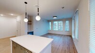 Located in the heart of downtown Raleigh, this well-appointed 2-bedroom, 2-bathroom residence offers a thoughtfully designed single-floor layout with modern finishes throughout. Light wood-tone flooring flows seamlessly across every room, creating a warm and cohesive aesthetic.

The open-concept kitchen and living area serves as the centerpiece of the home. The kitchen is outfitted with stainless steel appliances, two-tone cabinetry combining natural wood uppers with sage-green lowers, a tiled backsplash, white quartz countertops, and a central island. Stylish globe pendant lights hang above, adding a contemporary touch. The adjoining living area features large windows fitted with blinds, allowing abundant natural light and offering views of the Raleigh cityscape.

The primary bedroom is a generously sized retreat with a bank of windows framing urban views, complemented by a well-organized walk-in closet with built-in shelving and hanging systems. The second bedroom includes a ceiling fan and its own window with city views. Both bathrooms are finished with white subway tile surrounds, modern vanities with illuminated mirrors, and wood-look flooring. Additional spaces include a hallway, entrance, laundry room, utility room, and three closets, ensuring ample storage throughout.
