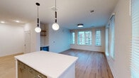 Located in the heart of downtown Raleigh, this well-appointed 2-bedroom, 2-bathroom residence offers a thoughtfully designed single-floor layout with modern finishes throughout. Light wood-tone flooring flows seamlessly across every room, creating a warm and cohesive aesthetic.

The open-concept kitchen and living area serves as the centerpiece of the home. The kitchen is outfitted with stainless steel appliances, two-tone cabinetry combining natural wood uppers with sage-green lowers, a tiled backsplash, white quartz countertops, and a central island. Stylish globe pendant lights hang above, adding a contemporary touch. The adjoining living area features large windows fitted with blinds, allowing abundant natural light and offering views of the Raleigh cityscape.

The primary bedroom is a generously sized retreat with a bank of windows framing urban views, complemented by a well-organized walk-in closet with built-in shelving and hanging systems. The second bedroom includes a ceiling fan and its own window with city views. Both bathrooms are finished with white subway tile surrounds, modern vanities with illuminated mirrors, and wood-look flooring. Additional spaces include a hallway, entrance, laundry room, utility room, and three closets, ensuring ample storage throughout.