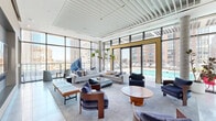 Located at 134 Steuben St in Jersey City, NJ, this generously proportioned amenity floor offers a sophisticated blend of modern design and versatile gathering spaces. Floor-to-ceiling curtain-wall glazing runs throughout, flooding the interiors with abundant natural light and framing panoramic views of the Jersey City skyline and beyond, with glimpses of the New York City skyline visible from the dining area.

The centerpiece lounge is an expansive, open-plan space featuring a structured white slat ceiling, elegant contemporary furnishings in neutral and navy tones, and large-format tile flooring. Sliding glass doors open directly onto an outdoor pool deck, seamlessly connecting indoor and outdoor living.

The combined dining room and kitchen is a standout space, showcasing bold cobalt-blue high-gloss cabinetry trimmed with brushed gold accents, a professional-grade gas range, white stone countertops, and a striking geometric tile floor. Pendant lighting and floor-to-ceiling windows complete the polished aesthetic.

A game room area offers a billiards table, a built-in upholstered banquette in rich blue velvet, and a gold-accented pendant light. A dedicated children's play room features soft pendant lighting, a mini slide, and vibrant play furnishings set against expansive greenery-framed windows. Refined hallways with gold elevator surrounds and recessed cove lighting provide elegant circulation throughout the floor.