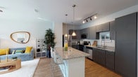 This well-appointed single-floor residence offers a thoughtfully designed open-concept layout that seamlessly connects the kitchen, dining, and living areas. The contemporary kitchen is a standout feature, showcasing sleek charcoal cabinetry, granite countertops, a large center island with bar seating, stainless steel appliances, and stylish pendant lighting complemented by track lighting overhead. Wood-look flooring runs throughout the main living areas, adding warmth and continuity to the space.

The living room is bright and inviting, benefiting from large sliding glass doors that open to an outdoor patio, flooding the interior with natural light and providing seamless indoor-outdoor living. A ceiling fan adds comfort to the room.

The bedrooms are carpeted for comfort and each features a ceiling fan. The primary bedroom offers generous proportions with a large window overlooking the outdoors, while a second bedroom provides equal comfort and flexibility. Both bedrooms share access to a full bathroom appointed with granite countertops, charcoal cabinetry, a combination tub and shower, and wood-look flooring consistent with the rest of the home.

A dedicated in-unit laundry room with a full-size washer and dryer and overhead shelving adds practical convenience, rounding out this functional and modern living space.