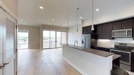 Located at 4525 Guadalupe St in Austin's vibrant 78751 neighborhood, this modern single-floor space showcases a clean, contemporary design with an open-concept layout that seamlessly connects the kitchen and living areas. Light hardwood flooring extends throughout, lending warmth and continuity to the space.

The kitchen is a standout feature, equipped with dark, floor-to-ceiling cabinetry that provides ample storage and creates a striking contrast against the bright white walls. A generous waterfall-edge island with a dark countertop serves as both a workspace and a social hub, complemented by stylish pendant lighting overhead. Stainless steel appliances, including a French door refrigerator with an in-door ice and water dispenser, complete the well-appointed kitchen.

The open living area benefits from an abundance of natural light streaming through large sliding glass doors that lead to an outdoor balcony, offering views of the surrounding Austin cityscape. Recessed lighting throughout ensures the space is well-lit at any time of day. The overall ambiance is modern, minimal, and inviting — ideal for those seeking a sleek urban living experience in the heart of Austin.