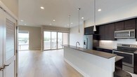 Located at 4525 Guadalupe St in Austin's vibrant 78751 neighborhood, this modern single-floor space showcases a clean, contemporary design with an open-concept layout that seamlessly connects the kitchen and living areas. Light hardwood flooring extends throughout, lending warmth and continuity to the space.

The kitchen is a standout feature, equipped with dark, floor-to-ceiling cabinetry that provides ample storage and creates a striking contrast against the bright white walls. A generous waterfall-edge island with a dark countertop serves as both a workspace and a social hub, complemented by stylish pendant lighting overhead. Stainless steel appliances, including a French door refrigerator with an in-door ice and water dispenser, complete the well-appointed kitchen.

The open living area benefits from an abundance of natural light streaming through large sliding glass doors that lead to an outdoor balcony, offering views of the surrounding Austin cityscape. Recessed lighting throughout ensures the space is well-lit at any time of day. The overall ambiance is modern, minimal, and inviting — ideal for those seeking a sleek urban living experience in the heart of Austin.