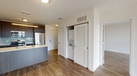 Located at 1317 N Wells Street in Chicago's sought-after Old Town neighborhood, this modern single-floor unit offers a thoughtfully designed open layout with high-quality contemporary finishes throughout. Rich hardwood-style flooring flows seamlessly across the living, dining, and kitchen areas, creating a cohesive and inviting atmosphere.

The kitchen is a standout feature, outfitted with dark espresso cabinetry, stainless steel appliances including a gas range, microwave, and French door refrigerator, complemented by clean white countertops and a light blue glass tile backsplash. A kitchen island provides additional prep and seating space, anchoring the open-concept living area.

The living space is bathed in natural light courtesy of expansive floor-to-ceiling windows that frame views of the surrounding Chicago streetscape, lending an airy, connected feel to the interior. Crisp white walls and clean architectural lines reinforce the unit's contemporary character.

A dedicated closet houses a stacked in-unit washer and dryer, adding everyday convenience. The bathroom is finished with large-format marble-look tile in the walk-in shower, a dark wood vanity with an undermount sink, and modern chrome fixtures, delivering a clean and polished aesthetic throughout.