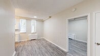 Located at 216 Fountain Street in New Haven, CT, this one-bedroom, one-bathroom unit offers a well-organized layout across a single floor. The entrance leads into a bright living room featuring light gray hardwood-style flooring, neutral beige walls, a textured ceiling, and a window that invites natural light while also accommodating a baseboard heater. A dedicated bedroom provides a comfortable, generously sized private retreat, complemented by two closets for ample storage. The galley-style kitchen is efficiently designed with white shaker cabinetry, marble-patterned countertops, a stainless steel sink, electric range, and a full-size refrigerator, alongside a window that brings in additional natural light. The bathroom is finished with white tile flooring, a white vanity with sink, and a walk-in shower stall equipped with sturdy grab bars, offering accessibility-friendly features. A private balcony extends the living space outdoors, offering a tree-lined neighborhood view of the surrounding New Haven streetscape. The unit's clean, neutral palette and functional layout make it a practical and comfortable living space in a well-established multi-story residential building.