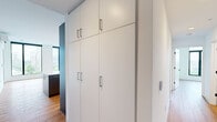 Located at 1237 N Van Buren St in Milwaukee, WI, this contemporary 3-bedroom, 2-bathroom residence offers a thoughtfully designed single-floor layout with modern finishes and impressive city views. The open-concept living room is a standout, featuring expansive floor-to-ceiling windows with bold black frames that frame sweeping views of the Milwaukee skyline and surrounding neighborhood, flooding the space with natural light. Warm-toned hardwood flooring flows seamlessly throughout the entire unit, creating a cohesive and inviting aesthetic. The kitchen is equipped with stainless steel appliances, sleek gray upper cabinetry, a white subway tile backsplash, and a large island with a clean white countertop and integrated sink, illuminated by a modern linear pendant light. The generously sized primary bedroom includes a walk-in closet with built-in shelving and a dedicated wall-mounted HVAC unit. Additional bedrooms are bright and well-proportioned, with easy access to the bathrooms. The bathrooms feature clean, minimalist design with sliding glass-door showers. A dedicated in-unit laundry space houses a full-size stacked washer and dryer. Built-in floor-to-ceiling storage cabinetry in the hallway adds exceptional organizational functionality to this well-appointed home.