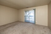 Located at 1800 Watrous Ave in Des Moines, Iowa, this two-bedroom, one-bathroom residence offers a practical and well-organized single-floor layout. The living area is carpeted and bathed in natural light, with a sliding glass door that opens to a private balcony overlooking surrounding trees — a standout feature that brings the outdoors in. Textured ceilings run throughout the main living spaces, adding a classic residential character.

The generously sized primary bedroom comfortably accommodates large furniture and includes direct access to a walk-in closet fitted with wood hanging rods and upper shelving for ample storage. The second bedroom also features carpet flooring, a window for natural light, and its own closet with built-in rod storage. Both bedrooms are finished in neutral tones, lending versatility for personalization.

The galley-style kitchen is equipped with dark wood cabinetry, white appliances including a range and refrigerator, a double-basin sink, and durable hardwood-style flooring — offering an efficient and functional cooking space. The bathroom includes a full tub-shower combination with chrome fixtures and a clean white surround. A hallway connects the rooms, providing a logical flow throughout the unit. This residence is a straightforward, functional home in a convenient Des Moines location.
