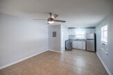 Located at 2580 Wild Pines Ct in Naples, FL, this one-bedroom, one-bathroom residence offers a practical and efficient single-floor layout. The open living and dining area provides a comfortable gathering space, featuring light tile flooring and a ceiling fan that promotes airflow throughout. Soft blue-gray walls and white trim create a clean, neutral palette across the entire unit.

The kitchen is well-equipped with white cabinetry, granite-look countertops, a stainless steel range, and a full-size stainless steel refrigerator. Multiple windows allow natural light to fill the space, enhancing the bright and airy feel. A window AC unit provides supplemental cooling.

The bedroom is a comfortable, sunlit room with tile flooring, a ceiling fan, a window AC unit, and a closet with a classic paneled door — providing essential storage.

The bathroom features a white vanity with a sink, a wall-mounted medicine cabinet mirror, and a tiled walk-in shower, maintaining the clean, functional aesthetic found throughout the unit.

With tile flooring in every room, easy-to-maintain finishes, and a straightforward layout, this residence is a practical option in the Naples, FL area.