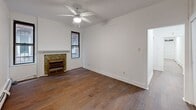 Located at 324 S Mathilda St in Pittsburgh's Bloomfield neighborhood, this single-floor unit combines classic architectural character with functional living spaces. Rich hardwood flooring runs throughout the entire unit, creating a warm and cohesive aesthetic from room to room. The main living area is a standout, featuring a decorative tile-surround fireplace, a ceiling fan with light fixture, and multiple windows that invite natural light and neighborhood views. A second room with its own ceiling fan and fireplace offers additional flexible living space. The kitchen is equipped with white cabinetry, a stainless steel refrigerator, and a sink, providing a clean and practical workspace. Bedrooms are bright and well-proportioned, with large windows framing views of the surrounding brick streetscape and ample closet space including a built-in bi-fold closet. The bathroom features classic white subway tile wainscoting, a soaking tub, and a window for natural ventilation. Baseboard heating is present throughout the unit. A glass door opens to a private wooden deck, offering an outdoor retreat with views of the street — a charming extension of the living space in a walkable urban setting.