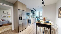 This well-appointed single-floor residence features four bedrooms and two bathrooms within a compact yet efficiently planned layout. The open-concept kitchen is outfitted with stainless steel appliances, including a full-size refrigerator with ice maker, electric range, and microwave, complemented by sleek flat-panel cabinetry that extends to the ceiling for maximum storage. A dining bar provides additional seating and separates the kitchen from the living area. The living room is a standout space, anchored by large floor-to-ceiling windows with black metal framing that flood the room with natural light and offer urban views. Light wood-tone flooring flows throughout the unit, contributing to a cohesive, modern aesthetic. The four bedrooms each feature soft sage-green accent walls, light wood flooring, and ceiling fans. The primary bedroom benefits from direct window access and city views. The remaining bedrooms offer comfortable, well-proportioned spaces. Both bathrooms are finished with light wood vanities, large wall mirrors, and soft gray-green walls. One bathroom includes a walk-in shower, while the other features a full tub-shower combination. The overall ambiance is modern, clean, and urban.