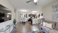 This single-floor residence offers a thoughtfully designed open-concept layout that seamlessly connects the living, dining, and kitchen areas. The living room features hardwood-style flooring, a ceiling fan, and a sliding glass door that fills the space with natural light while providing direct access to a private balcony with exterior views.

The kitchen is well-appointed with dark espresso cabinetry, white quartz countertops, stainless steel appliances including a refrigerator, gas range, and microwave, and a peninsula with bar seating. The galley-style kitchen layout maximizes efficiency, and pendant lighting adds a refined touch overhead.

The dining area accommodates a glass-top table beneath an elegant chandelier, accompanied by a built-in shelving nook for additional storage. Decorative mirrors along the wall enhance the sense of space.

The bedroom is carpeted for comfort, featuring a ceiling fan and a window with outdoor views. A walk-in closet with wrap-around shelving and hanging rods provides generous storage. The bathroom includes a white quartz vanity, undermount sink, built-in open shelving, and a tub-shower combination, all finished in a clean, neutral palette throughout.