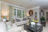 Located in Atlanta's desirable Virginia-Highland area, this single-floor residence offers a thoughtfully designed layout with a warm, sophisticated aesthetic throughout. The living room is bright and generously proportioned, featuring crown molding, large windows that flood the space with natural light and views of surrounding greenery, and plush carpeting — creating an inviting atmosphere for both relaxing and entertaining. The kitchen is equipped with stainless steel appliances, rich dark wood cabinetry, granite countertops, and a decorative tile backsplash, complemented by a bold geometric accent wall that adds personality to the space. Multiple bedrooms provide comfortable retreats; the primary suite includes a walk-in closet and large windows, while additional bedrooms feature textured accent walls and ample natural light. The bathrooms are well-appointed throughout — one features striking leaf-patterned wallpaper with a pedestal sink, while another offers a full vanity with granite counters and a tub-shower combination. A second full bath echoes this design with teal accent walls and tile flooring. The overall ambiance is polished and cohesive, blending neutral tones with carefully chosen accent details across every room.