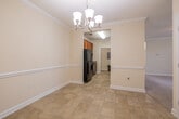 This single-floor residence offers a thoughtfully designed layout with consistent, classic finishes throughout. The galley-style kitchen is a functional centerpiece, featuring warm wood cabinetry, granite countertops, a stainless steel sink, and black appliances including a refrigerator, range, microwave, and dishwasher. A pendant chandelier in the adjacent dining area adds an elegant touch, visible from the kitchen's open sightline.

Crown molding runs throughout the main living areas, adding a refined architectural detail against the warm beige walls. Tile flooring in the kitchen and utility areas transitions to plush carpeting in the bedrooms and living spaces. A dedicated utility room houses the electrical panel and provides additional functional space.

The bedrooms are bright and generously sized, each featuring large windows with blinds that allow for natural light and views of the surrounding neighborhood. The primary bedroom benefits from a ceiling fan, crown molding, and direct access to an en-suite bath. The bathrooms are finished with granite-topped wood vanities, tile flooring, and a shower-tub combination. A large double-door closet provides ample storage. Overall, the space presents a clean, neutral palette ideal for comfortable everyday living.