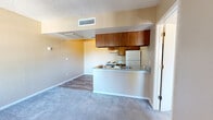 Located at 100 E Golf Links Rd in Sierra Vista, Arizona, this one-bedroom, one-bathroom unit offers a thoughtfully organized single-floor layout designed to maximize every square foot. The open-concept living and kitchen area forms the heart of the unit, where wood-look vinyl flooring transitions seamlessly between spaces. The kitchen features warm-toned wood cabinetry, a peninsula with a built-in sink and countertop workspace, a coil-top electric range, and a full-size refrigerator — all set beneath a textured ceiling with overhead ventilation. The adjacent living area is finished with plush neutral carpet, providing a comfortable and inviting atmosphere. The bedroom is a well-proportioned, carpeted retreat with a large window that invites natural light and views of the surrounding neighborhood. A dedicated closet with built-in shelving offers practical storage. The bathroom is outfitted with a full tub-shower combo featuring white tile surround, a single vanity with countertop sink, and wood-look flooring that ties the space together. Neutral warm-beige tones carry throughout the unit, lending a cohesive and clean aesthetic. The unit's efficient design makes it a practical option for individuals seeking a well-equipped residence in Sierra Vista.