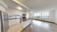Located at 65 Forest Manor Rd in Toronto's north end, this well-appointed 3-bedroom, 1-bathroom unit offers a generous and functional layout across a single floor. The modern kitchen is a standout feature, fitted with stainless steel appliances including a full-size refrigerator, electric range, and built-in microwave. White shaker cabinetry, a subway tile backsplash, dark countertops, and a central island provide ample storage and prep space, while light tile flooring ties the look together cleanly.

The open living room is bathed in natural light from large windows overlooking the surrounding neighbourhood, and features classic parquet wood flooring that carries throughout all three bedrooms. Each bedroom is generously proportioned — the primary bedroom is notably spacious — and benefits from large windows with urban views and baseboard heating. Mirrored sliding closet doors in the primary bedroom add both storage and a sense of depth.

The bathroom is finished with crisp white subway tile surrounding a full soaker tub and shower combination, maintaining a clean and timeless aesthetic. A connecting hallway links all rooms efficiently. The overall ambiance is bright, neutral, and move-in ready, offering a comfortable urban living experience in a well-established Toronto location.