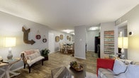 Located at 1400 Patricia in San Antonio, Texas, this single-floor model unit offers a well-designed, open-concept layout that seamlessly connects the living, dining, and kitchen areas. The living room is highlighted by wood-look flooring, a textured ceiling, and a large sliding glass door with vertical blinds that allows generous natural light to fill the space. A built-in shelving unit adds both functionality and character to the room.

The dining area is positioned adjacent to the living room, separated by a half-wall with a pass-through counter that connects to the kitchen. The galley-style kitchen is efficiently laid out with dark cabinetry, a double-basin sink, matching black appliances including a refrigerator and range, and ample upper and lower cabinet storage.

The bedrooms feature plush carpeting, ceiling fans, and windows with blinds that provide natural light and privacy. Closet space is conveniently accessible from each bedroom. The bathroom is clean and functional, featuring wood-look flooring, a shower-tub combination, and a toilet, all within a compact, well-organized layout.

Throughout the unit, neutral gray walls and consistent wood-look flooring create a cohesive, modern aesthetic, making this a comfortable and practical living space in the heart of San Antonio.