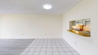 Located at 9060 NW 8th Street in Miami, FL, this two-bedroom, two-bathroom apartment offers a well-organized single-floor layout designed for comfortable living. The living room is a generously sized, open space featuring a mix of light gray laminate flooring and classic white tile, with a pass-through window connecting to the kitchen — a practical design touch that enhances the sense of openness. Neutral warm-toned walls and a textured ceiling carry throughout, giving the home a bright and airy feel.

The primary bedroom is notably spacious, bathed in natural light from a large window that frames views of lush greenery and the surrounding neighborhood. It is complemented by a roomy walk-in closet with dual hanging rods, offering ample storage. The second bedroom also features laminate flooring, warm walls, and a well-sized reach-in closet. Both bathrooms are finished with tile flooring; one features a tub-shower combination with decorative tile accenting and a sliding glass door enclosure. Each bathroom includes a vanity with storage cabinetry and a large mirror. Two hallways provide smooth connectivity throughout the unit. A private balcony overlooks a dense canopy of tropical trees, offering a serene outdoor retreat above the Miami skyline.