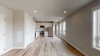 This thoughtfully designed single-floor unit showcases a clean, contemporary aesthetic throughout. The open-concept layout connects the kitchen and living area seamlessly, creating a bright and functional living space. Light wood-tone luxury vinyl plank flooring runs throughout, complementing the neutral gray and white color palette.

The kitchen is well-appointed with white shaker-style cabinetry reaching the ceiling for ample storage, stainless steel appliances including a refrigerator, range, microwave, and dishwasher, and a functional countertop workspace. Recessed lighting illuminates the area evenly.

The living space is generously proportioned, with large windows along one wall drawing in natural light and offering views of the surrounding neighborhood. Additional bedrooms feature light-filled windows, some with elevated urban views, and continue the light hardwood flooring aesthetic.

The bathrooms are finished with a modern touch, featuring walk-in tile showers with subway tile surrounds and brushed nickel fixtures. One bathroom includes a floating vanity with an undermount sink and a backlit LED mirror, adding a refined, contemporary detail. Warm terra cotta tile flooring grounds the bathroom spaces. Overall, the unit presents a fresh, move-in-ready environment with consistent modern finishes throughout.