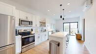 Located at 100 N Farwell St in Eau Claire, WI, this thoughtfully designed one-bedroom, one-bathroom unit offers a bright and modern living experience. The open-concept layout seamlessly connects the kitchen and living area, maximizing the efficient use of space. The kitchen is a standout feature, showcasing white shaker cabinetry, a subway tile backsplash, stainless steel appliances, open wood shelving, and a large center island with bar seating — all illuminated by stylish pendant lighting and recessed ceiling lights. Light hardwood flooring flows throughout, complementing the clean, white walls. The living room is anchored by a bold black-framed sliding glass door that opens to a private balcony with city views, flooding the space with natural light. A wall-mounted mini-split system provides climate control. The bedroom is a serene retreat with a tall, black-framed window that frames outdoor greenery and maintains the modern aesthetic. The bathroom features a wood-toned vanity with a white countertop, matte black fixtures, and a clean tiled floor. A dedicated closet provides practical storage. The overall ambiance is fresh, minimalist, and contemporary, ideal for those seeking a well-appointed urban residence.