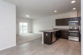 This single-floor residence features a thoughtfully designed open-concept layout connecting the kitchen and living area. The kitchen is well-appointed with dark espresso cabinetry, granite-style countertops, stainless steel appliances including a refrigerator, electric range, and built-in microwave, along with a peninsula that provides additional counter space and separates the kitchen from the living area. Light wood-style flooring runs throughout the kitchen and entry areas, while plush neutral carpeting extends through the living space and bedrooms.

The bedrooms are bright and generously sized, each featuring large windows with exterior views and ample natural light. One bedroom includes a spacious walk-in closet outfitted with wire shelving and hanging rods along multiple walls. The unit includes two full bathrooms, both finished with dark cabinetry, light-toned countertops, chrome hardware, and beige tile flooring. One bathroom features a tub-shower combination, while the other includes a separate soaking tub. Both bathrooms are equipped with chrome towel bars. Throughout the unit, crisp white walls, recessed lighting in key areas, and clean architectural lines contribute to a bright, contemporary ambiance.