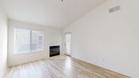 Located at 2991 College Ave in Livermore, CA, this single-floor, 3-bedroom, 2-bathroom residence offers a clean, modern aesthetic defined by crisp white walls and light wood-style flooring that runs consistently throughout the home. The open living room immediately impresses with soaring vaulted ceilings that amplify the sense of space, large windows with blinds that invite abundant natural light, and a sleek fireplace that serves as a focal point. A pass-through opening connects the living area to the galley-style kitchen, which features white cabinetry, ample counter space, a gas range, and black appliances including a full-size refrigerator. The spacious primary bedroom includes a dedicated walk-in closet fitted with wire shelving and hanging rods. Additional bedrooms are well-proportioned, each with closet access — one featuring mirrored sliding closet doors. Both bathrooms are finished in a neutral palette with white cabinetry, solid-surface countertops, large mirrors, and brushed nickel hardware; one includes a shower/tub combination with a window for natural light. A hallway connects all rooms efficiently. The home's consistent flooring, vaulted ceiling in the main living area, and bright, neutral finishes create a cohesive and welcoming atmosphere throughout.