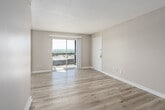 Located at 2700 Temple Crest Drive in Birmingham, Alabama, this one-bedroom, one-bathroom unit offers a well-organized layout across a single floor. The combined kitchen and living room serves as the heart of the space, featuring light wood-style flooring that runs throughout and neutral warm-toned walls that create a clean, cohesive aesthetic. The kitchen is equipped with white cabinetry, white appliances including a refrigerator and electric range, and ample counter space. The living area benefits from a large window and sliding glass doors that open onto a private balcony, where expansive views of the surrounding Birmingham treeline and skyline can be enjoyed. Natural light flows generously into the main living area. The bedroom is a comfortable, well-proportioned room with its own window, textured ceiling, and easy access to a hallway closet for added storage. The bathroom features a full tub-shower combination with white tile surround, complemented by the same light flooring found throughout the unit. A dedicated hallway connects the rooms efficiently, and the entryway provides a welcoming transition into the space. Textured ceilings are consistent throughout, adding a classic touch to the overall interior character.