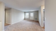 This single-story home offers a functional and well-organized layout across five bedrooms, two bathrooms, a living room, and a kitchen. The living room serves as a welcoming entry point, featuring neutral-toned walls, plush wall-to-wall carpeting, and a front door with a gridded window that allows natural light to fill the space. An additional side window further brightens the room, creating an open and airy feel.

The kitchen is thoughtfully designed with white shaker-style cabinetry, light granite-style countertops, and a peninsula that adds extra prep space. Black appliances — including a range, microwave, dishwasher, and refrigerator — provide a striking contrast against the white cabinetry, while wood-look flooring adds warmth underfoot.

Both bathrooms are clean and efficiently laid out, each featuring a full tub-shower combination, white vanity with storage, and wood-look flooring that complements the overall aesthetic. The bathrooms maintain a bright, neutral palette consistent with the rest of the home.

The five bedrooms are carpeted and bathed in natural light through windowed blinds. The spacious primary bedroom offers ample room, while the additional bedrooms provide versatile space suitable for various uses. Two hallways connect the rooms seamlessly, contributing to a cohesive and navigable floor plan throughout the home.