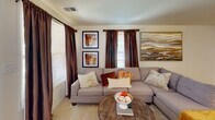 This two-floor residence offers a thoughtfully designed layout with a welcoming flow between its main living spaces. The open-plan living and dining area forms the heart of the home, where the living room features multiple windows dressed with rich drapes that invite natural light, complemented by neutral carpet flooring throughout. The dining area is anchored by an elegant chandelier and arched mirror accents, creating a refined yet relaxed atmosphere.

The kitchen is efficiently laid out with warm wood cabinetry, gray laminate countertops, a double-basin sink, and white appliances including a refrigerator, dishwasher, and stovetop. It connects seamlessly to the dining space, making entertaining convenient.

The primary bedroom is generously proportioned with soft carpet, large windows, and a calm neutral palette. A secondary bedroom provides comfortable accommodations with a closet and matching carpet flooring. The full bathroom includes a glass-enclosed walk-in shower with tile surround and a bright window, while a compact half-bath serves as a practical powder room. A dedicated laundry area houses a full-sized washer and dryer alongside utility storage, adding everyday convenience to this well-rounded multi-floor home.