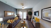 Located at 3001 S New Rd in Waco, Texas, this single-story residence offers a thoughtfully designed layout with a cohesive, contemporary aesthetic. The entryway welcomes visitors with hardwood-style flooring and tasteful wall art, setting the tone for the rest of the home. The living room is a standout space, featuring dark hardwood-style floors, a ceiling fan, dual-tone drape panels framing a glass patio door, and an accent wall that adds depth and character. The kitchen is equipped with rich wood cabinetry, granite-style countertops, a mosaic tile backsplash, and black appliances including a range, microwave, refrigerator, and dishwasher — providing ample functionality and storage. The primary bedroom is carpeted and bright, with natural light filtering through large windows adorned with two-tone curtains and a ceiling fan overhead. The en-suite bathroom features a wide vanity with warm wood cabinetry, granite-style countertops, a large mirror with bar lighting, and a full tub-shower combo. A second bedroom offers a comfortable, intimate layout with closet access. The second bathroom mirrors the clean, functional design of the primary bath with a tub-shower and hardwood-style flooring throughout.