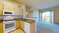 Located at 4800 Tassajara Road in Dublin, CA, this one-bedroom, one-bathroom residence offers a thoughtfully designed single-story layout with a comfortable and functional living environment. The open-concept kitchen and living area serves as the heart of the home, featuring light wood cabinetry, granite-style countertops, a full suite of white appliances including a gas range, microwave, dishwasher, and refrigerator, and a breakfast bar peninsula. Wood-style flooring runs throughout the kitchen, transitioning to plush carpet in the living and bedroom areas. The spacious living room is bathed in natural light, enhanced by track lighting and direct access to a private balcony through sliding glass doors, offering pleasant outdoor views. The bedroom is generously sized with large windows that frame scenic views of the surrounding neighborhood and hills, filling the room with abundant natural light. The full bathroom is clean and well-appointed, featuring a tub/shower combination, light wood vanity, and tile flooring. Additional conveniences include a hallway, a dedicated closet for storage, and an entry door with window. Warm neutral tones and soft lighting throughout create a bright, welcoming ambiance.