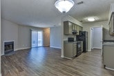 Located in Fayetteville, GA, this single-story home offers a well-designed layout with a blend of practical finishes and comfortable living spaces throughout. The open living and dining area is highlighted by warm hardwood-style flooring, neutral walls, and a sliding glass door that invites natural light and provides access to the outdoors. A fireplace serves as a focal point in the living area, adding warmth and character to the space. An elegant pendant light fixture defines the dining area, creating a clear and inviting zone for gatherings. The galley-style kitchen is efficiently arranged with ample sage-toned cabinetry, granite-look countertops, black appliances including a range and refrigerator, and wood-look flooring that carries through from the main living areas. The bedrooms are carpeted for comfort and each feature ceiling fans and windows that bring in natural light. The primary bedroom includes direct access to a walk-in closet and an en-suite bathroom. Both bathrooms are finished with gray-toned vanities, granite-style countertops, and tub-shower combinations with brushed nickel fixtures. Textured ceilings and clean white trim complete the cohesive, move-in-ready aesthetic throughout this Fayetteville home.