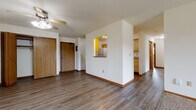 Located in Madison, WI (53719), this single-floor unit offers a practical and well-organized layout designed for comfortable everyday living. The main living area greets you upon entry, featuring durable wood-look plank flooring, warm wood baseboard trim, and a ceiling fan with light fixture. A distinctive pass-through window connects the living space to the kitchen, adding an open, communicative feel between the two areas. The galley-style kitchen is efficiently designed with ample honey-toned wood cabinetry on both sides, laminate countertops, a double sink, and white appliances including a range, refrigerator, and over-the-range microwave. A dedicated pantry closet provides additional storage. The living room extends toward a sliding glass door with access to an outdoor area, and is equipped with a wall-mounted HVAC unit. The bedrooms are carpeted for comfort, each featuring baseboard heating, windows with blinds that bring in natural light and outdoor greenery views, and generous closet space with sliding or hinged wood-panel doors. The full bathroom offers a long vanity with wood cabinetry, a mirror, and a tub/shower combination, all finished with wood-look flooring. A washer and dryer are also visible within the unit, adding convenience.