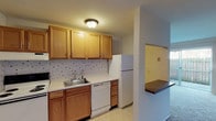 This single-floor unit at 1725C presents a well-organized layout with a practical kitchen, comfortable living spaces, and multiple bedrooms. The kitchen is equipped with warm-toned oak cabinetry, ample upper and lower storage, a decorative tile backsplash, and white appliances including a range, dishwasher, and refrigerator. Light-toned countertops and a stainless steel sink complete the functional workspace, with tile flooring underfoot.

The living areas are carpeted throughout, offering a comfortable feel. The main living space benefits from a sliding glass door that opens to a private patio with a fenced outdoor area, allowing natural light to filter in. A ceiling fan adds practicality to one of the adjoining areas, which connects seamlessly to the rest of the unit.

The bedrooms are carpeted and feature neutral walls. One bedroom includes built-in closets with louvered doors, a built-in vanity with lighting, and a window overlooking a tree-lined outdoor view. A second bedroom also features a window with natural light and a ceiling-mounted light fixture. The bathroom includes a tub and shower combination with sliding frosted glass doors, a single-sink vanity with oak cabinetry, and tile flooring, rounding out this straightforward and functional unit.