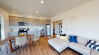 Located near the I-880 corridor in Oakland, CA, this contemporary multi-bedroom unit offers a thoughtfully designed single-floor layout that blends modern aesthetics with everyday functionality. The entry hallway features light wood-style flooring, recessed lighting, and clean white walls, setting a bright and welcoming tone throughout the space. The open-concept living, dining, and kitchen area serves as the heart of the unit, offering a generous and well-connected layout. The kitchen is equipped with stainless steel appliances including a gas range, microwave, dishwasher, and refrigerator, complemented by light wood cabinetry and clean countertops. Large floor-to-ceiling windows in the living and dining areas flood the space with natural light and frame views of the surrounding Oakland cityscape and highway infrastructure. A dedicated in-unit laundry area with a stacked washer and dryer adds convenience. Two well-proportioned bedrooms each feature carpeted floors, large windows with urban views, and ample natural light. The bathroom is finished in a clean, minimalist style with a combined tub and shower, tile flooring, and a modern vanity. Throughout the unit, the consistent use of light tones and contemporary finishes creates a cohesive, modern living environment.