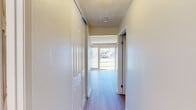 Located at 1240 East Avenue S in Palmdale, CA, this single-story, one-bedroom, one-bathroom unit offers a practical and well-organized layout across a compact but efficient floor plan. The combined kitchen and living room forms the heart of the space, featuring light hardwood-style flooring that flows throughout the unit. The living area is bright and airy, with large sliding glass doors and floor-to-ceiling vertical blinds that invite abundant natural light and provide direct views of the outdoor greenery. A ceiling fan adds comfort to the living space. The kitchen is finished with white cabinetry, light granite-style countertops, a double-basin sink, and a white coil-top range with an overhead exhaust hood, providing functional cooking space. A hallway connects the main living area to the private quarters, lined with a large closet for ample storage. The bedroom is a comfortable, well-proportioned room with a window fitted with vertical blinds, textured ceiling, and the same hardwood-style flooring. The bathroom includes a vanity with storage, a toilet, and a tub-shower combination, all finished in clean white tones. The textured ceilings are consistent throughout the unit, contributing to a uniform, tidy aesthetic.