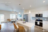 Located at 9000 Little Palm Way in Venice, FL, this well-appointed single-story home offers 2 bedrooms, 2 bathrooms, and a thoughtfully designed open-concept layout. The kitchen is a standout feature, showcasing crisp white shaker cabinetry, a grey subway tile backsplash, stainless steel appliances, quartz countertops, and a central island with seating — ideal for casual dining and entertaining. It flows seamlessly into the bright living room, which is bathed in natural light and finished with light wood-tone flooring that runs throughout the home. Both bedrooms are comfortably sized, with the primary bedroom offering ample space, and each room features windows that invite natural light. The two bathrooms are finished with white cabinetry, quartz vanities, and tiled tub-shower combinations. A dedicated laundry room with a full-size washer and dryer adds everyday convenience. Three closets provide generous storage throughout. A hallway connects the private quarters with clean, neutral-toned walls enhancing the airy feel. Outside, a private fenced yard with lush artificial turf and a patio area offers a low-maintenance outdoor retreat. The home's light blue lap siding exterior complements the serene Florida surroundings.
