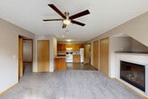 Located at 1016 Haeffele Way in Bloomington, Illinois, this single-floor, 2-bedroom, 2-bathroom home offers a practical and comfortable layout. The combined living and dining area serves as the heart of the home, featuring plush carpeting, a ceiling fan with light fixture, and a corner fireplace that adds a cozy focal point. French doors lead to the outdoors, filling the space with natural light. The kitchen is thoughtfully appointed with warm oak cabinetry, granite-style countertops, tile flooring, and white appliances including a dishwasher, range, and built-in microwave. A peninsula provides added counter space and casual dining potential. Both bedrooms are carpeted and equipped with ceiling fans; the primary bedroom includes a spacious closet. The two bathrooms feature granite-topped vanities with oak-framed mirrors and tile flooring. Additional conveniences include four closets for ample storage, a dedicated laundry area, a utility room, and a hallway connecting all spaces. The neutral color palette and consistent wood-tone accents throughout create a cohesive, move-in-ready environment suited for comfortable everyday living.