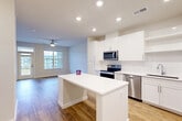 Located on Loblolly Place in La Plata, Maryland, this 1-bedroom, 1-bathroom residence offers a thoughtfully designed single-floor layout with a bright, modern aesthetic. The open-concept living area seamlessly integrates the kitchen, dining, and living spaces, all finished with warm hardwood-style flooring and recessed lighting. Ceiling fans are installed throughout, providing both function and comfort.

The kitchen is a standout feature, equipped with crisp white shaker cabinetry, a white quartz countertop, a subway tile backsplash, and a full suite of stainless steel appliances including a range, microwave, dishwasher, and refrigerator. A central island provides additional prep space and casual seating. Large windows in the living area allow generous natural light and offer views of the surrounding community, while a door leads to a private balcony.

The bedroom is a comfortable retreat with plush carpeting, a ceiling fan, and a large window with outdoor views. It is served by four closets, offering exceptional storage. The full bathroom features a soaking tub, a white vanity with quartz countertop, and hardwood-style flooring. Clean white walls and neutral tones throughout give the space a fresh, move-in-ready feel.
